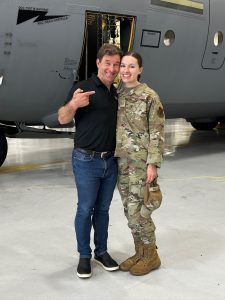 Olivia Giuffria in uniform standing next to her dad in front of military aircraft in a hangar.