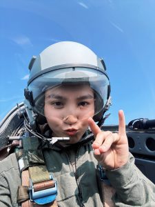 Zhiling Lin in the cockpit of a plane with a helmet and harness on.