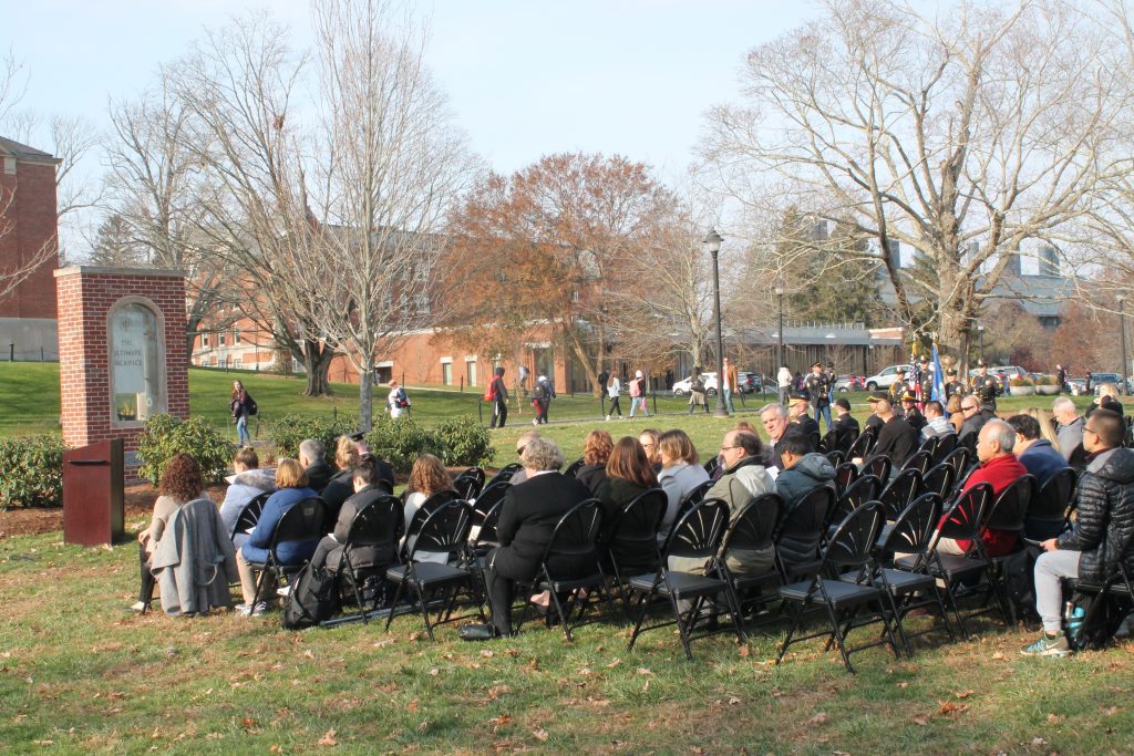 Members of the UConn community participating in the annual Veterans Day Ceremony, sitting outside, near the Ultimate Sacrifice Memorial.